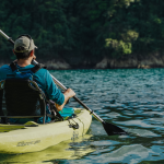 Man kayaking on calm Pacific waters surrounded by tropical rainforest in Costa Rica.