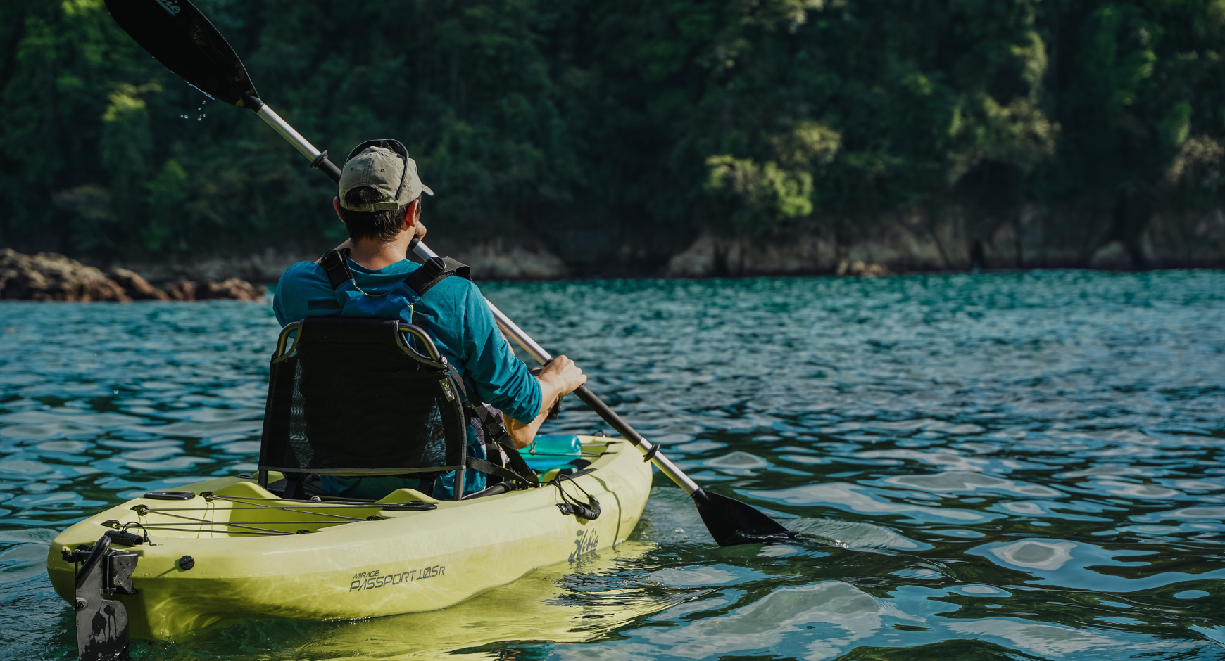 Man kayaking on calm Pacific waters surrounded by tropical rainforest in Costa Rica.
