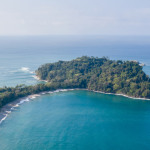 Aerial view of Manuel Antonio National Park, Costa Rica, showing lush jungle coastline and turquoise Pacific waters.