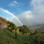 Scenic rainbow over lush mountains and country road in Costa Rica.