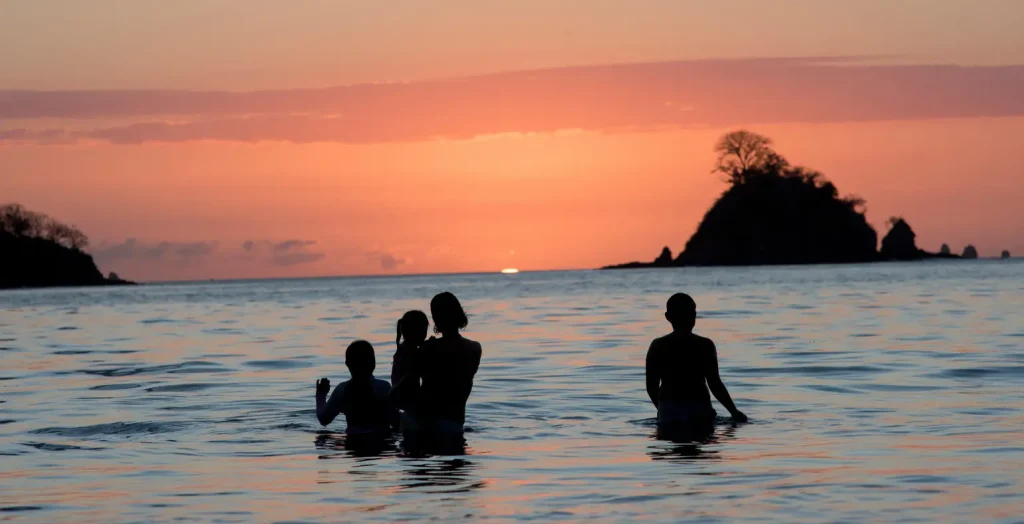 Family enjoying a tropical sunset on the beach in Costa Rica.