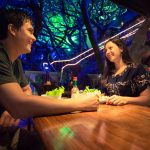 Couple enjoying dinner at a treehouse-themed restaurant in Costa Rica with glowing forest decor.