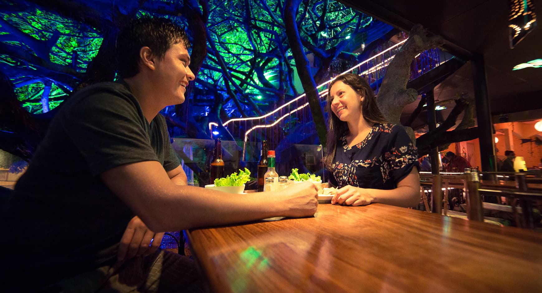 Couple enjoying dinner at a treehouse-themed restaurant in Costa Rica with glowing forest decor.