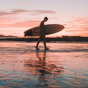 Silhouette of a surfer walking along the beach at sunset in Costa Rica.