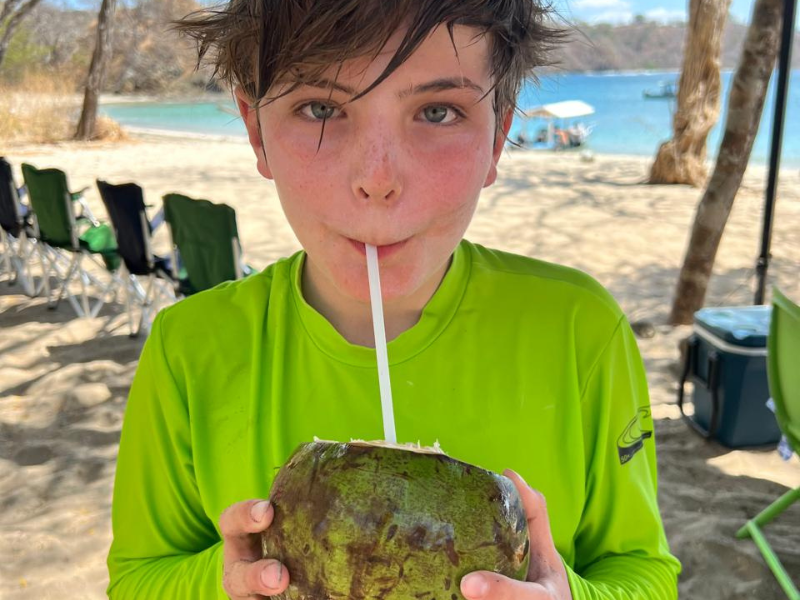 child drinking coconut on tamarindo beach