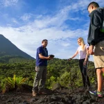 Tour guide showing volcanic rock to travelers during a hike near Arenal Volcano, Costa Rica.