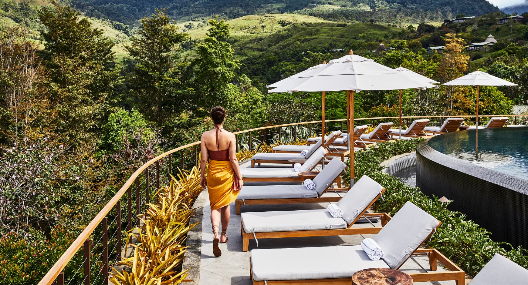 Woman walking by an infinity pool at a luxury wellness retreat in Pérez Zeledón, surrounded by green mountain views.