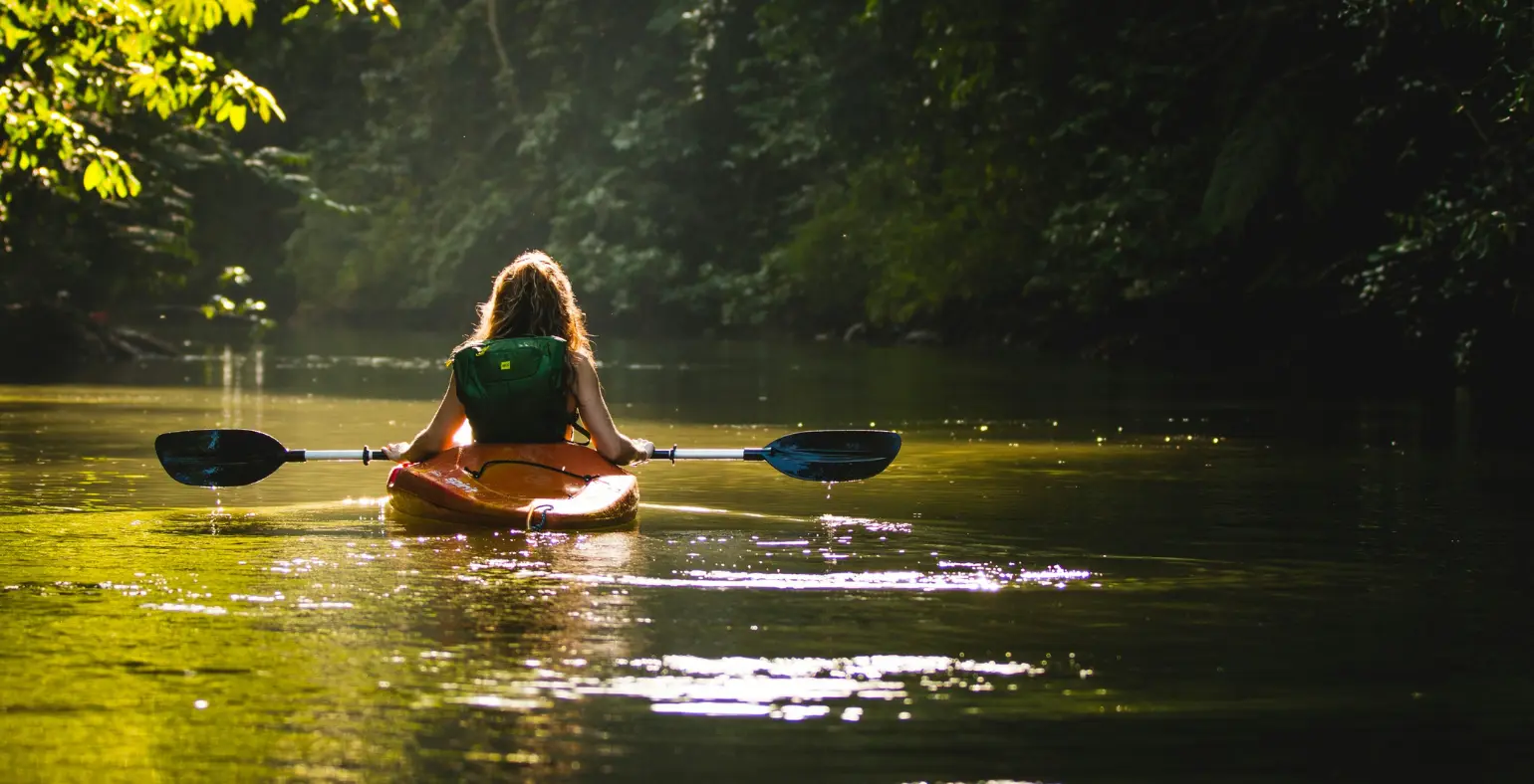 Person kayaking on a calm river surrounded by rainforest in Costa Rica
